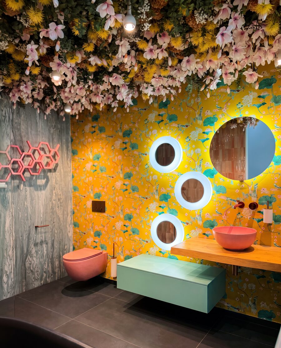 Gäste-WC mit gelber Blumentapete, Blütendecke, mintgrünem Waschtisch und korallenfarbener Keramik